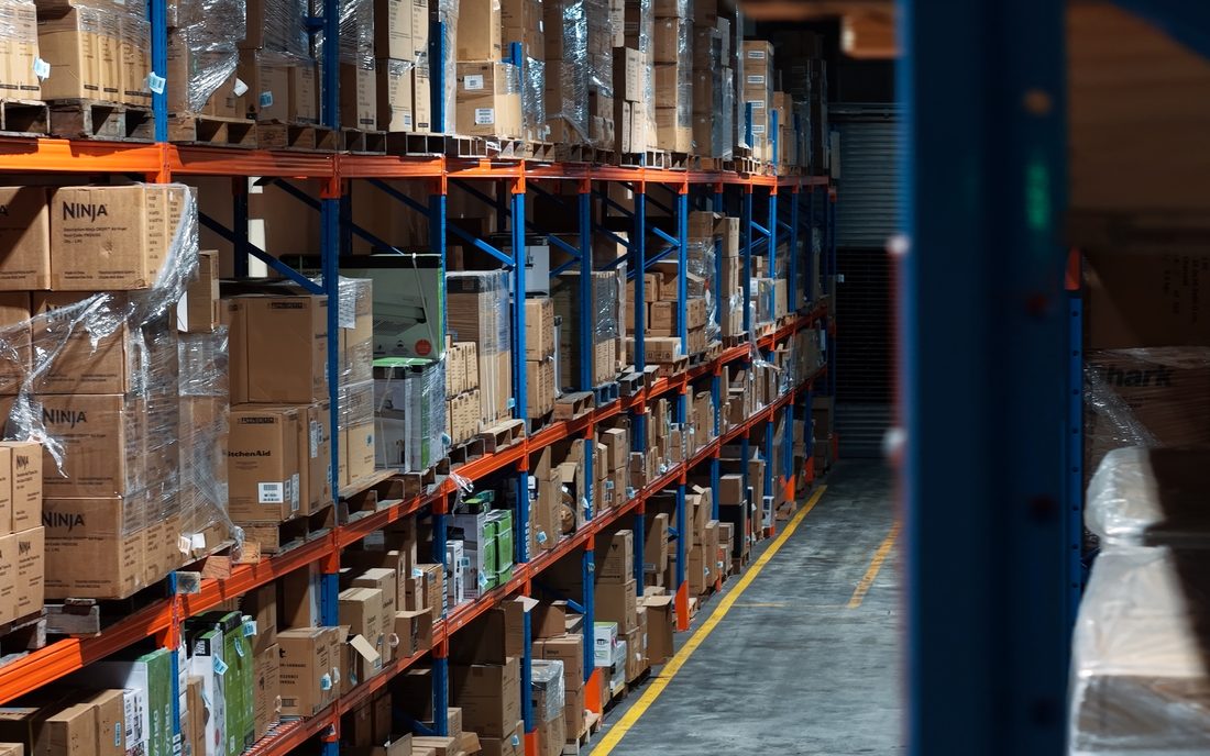 Pasillo de racks con inventario de electrodomésticos en la bodega de Ashram Logistics